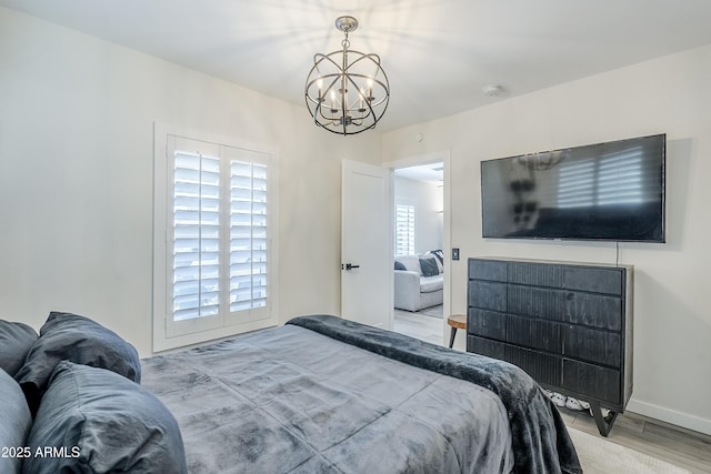 bedroom with baseboards, a chandelier, and wood finished floors