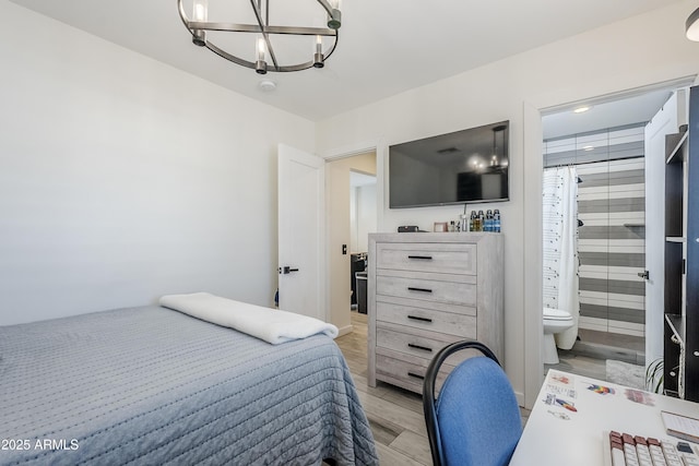 bedroom featuring light wood-type flooring, a notable chandelier, and ensuite bathroom