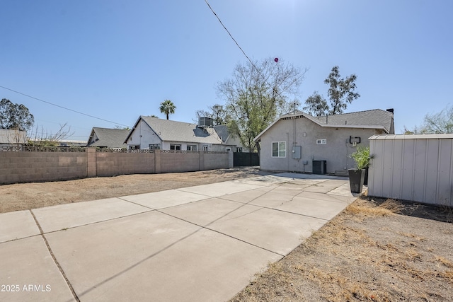 exterior space with central air condition unit, stucco siding, a fenced backyard, and a patio