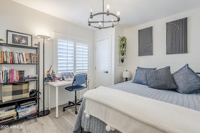 bedroom featuring light wood-style floors and an inviting chandelier