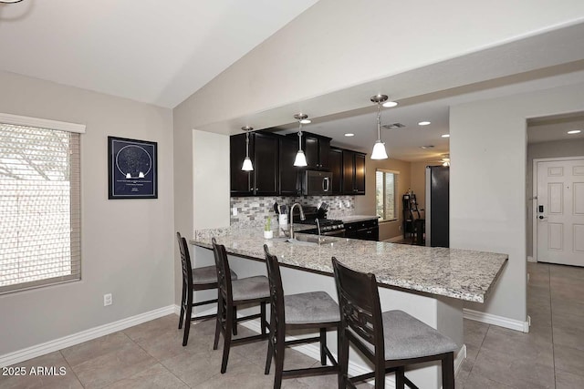 2005 E Anderson Dr E, Phoenix, AZ 85022 - kitchen featuring appliances with stainless steel finishes, decorative backsplash, light stone countertops, a peninsula, and a breakfast bar