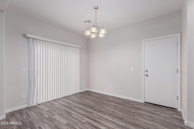 spare room featuring wood-type flooring and an inviting chandelier