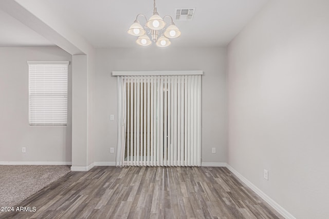 unfurnished room featuring a notable chandelier and hardwood / wood-style flooring