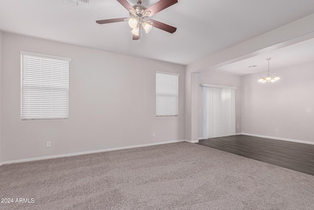 empty room featuring ceiling fan with notable chandelier and carpet flooring