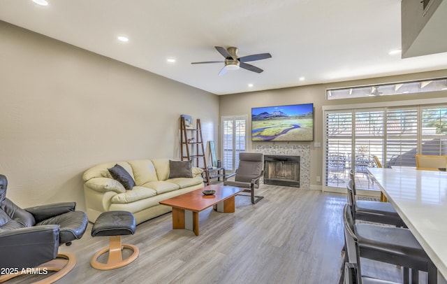 living room featuring a wealth of natural light, light hardwood / wood-style flooring, and a tile fireplace