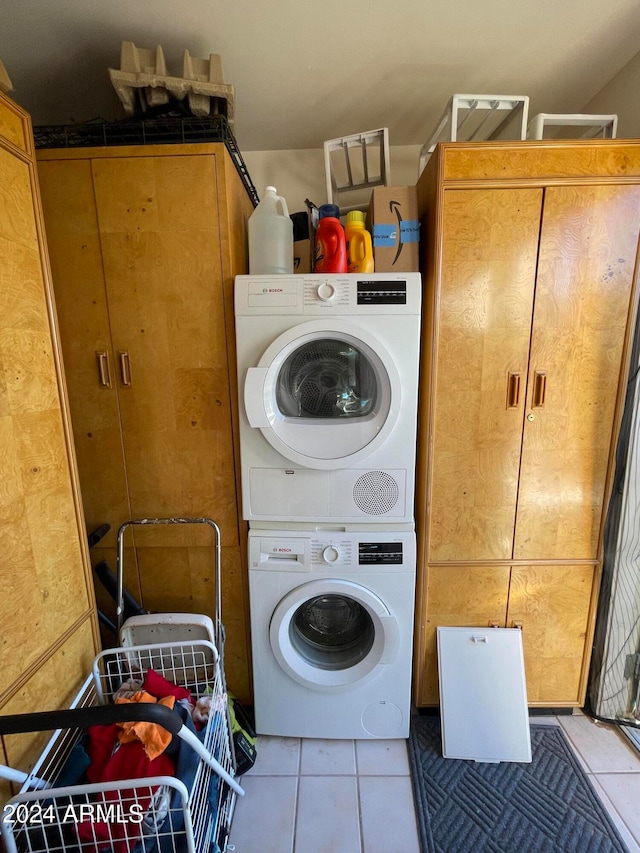 washroom with stacked washer / drying machine and light tile patterned flooring