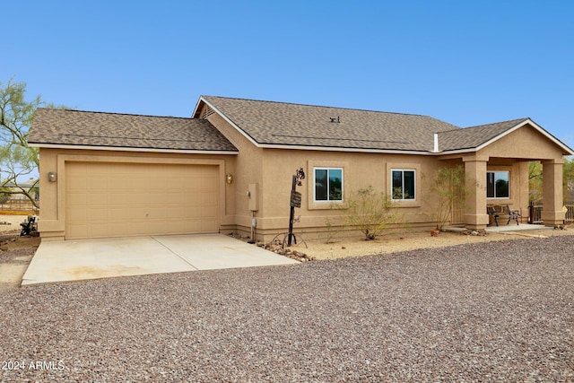 ranch-style house featuring an attached garage, roof with shingles, concrete driveway, and stucco siding