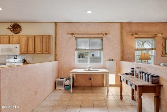 kitchen featuring light tile patterned floors, recessed lighting, light brown cabinetry, stove, and white microwave