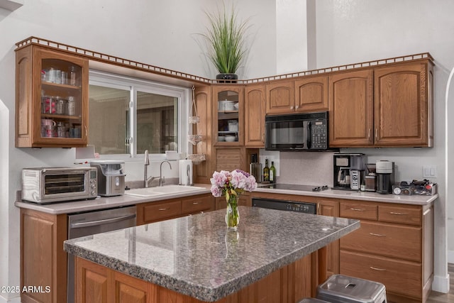 kitchen featuring a sink, brown cabinetry, black appliances, a toaster, and glass insert cabinets
