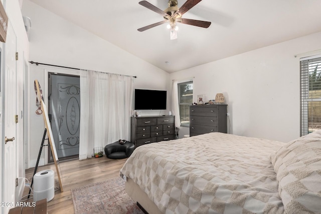 bedroom with a ceiling fan, vaulted ceiling, and wood finished floors