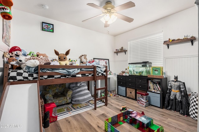 bedroom featuring wainscoting, ceiling fan, and wood finished floors