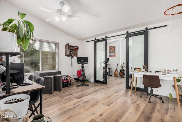office space with ceiling fan, lofted ceiling, a barn door, and light wood-type flooring