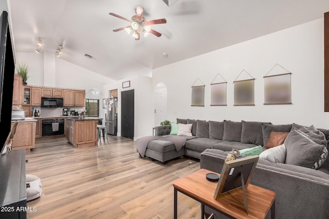 living room featuring high vaulted ceiling, visible vents, light wood finished floors, arched walkways, and a ceiling fan