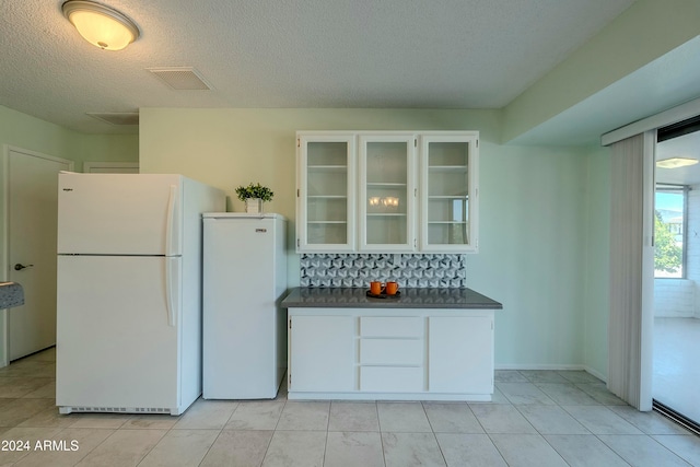 kitchen featuring white cabinets, white fridge, light tile patterned floors, and a textured ceiling