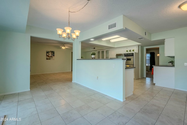 kitchen featuring white cabinetry, light tile patterned flooring, decorative light fixtures, and a textured ceiling