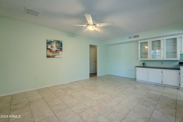 spare room with light tile patterned floors, a textured ceiling, and ceiling fan