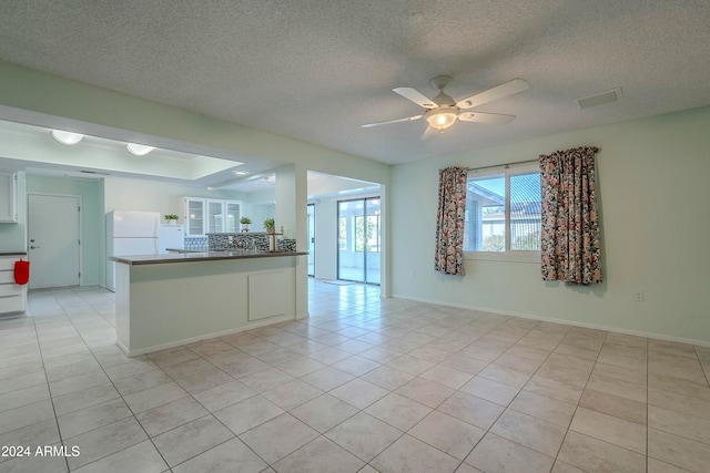 kitchen featuring light tile patterned flooring, backsplash, ceiling fan, a textured ceiling, and white fridge