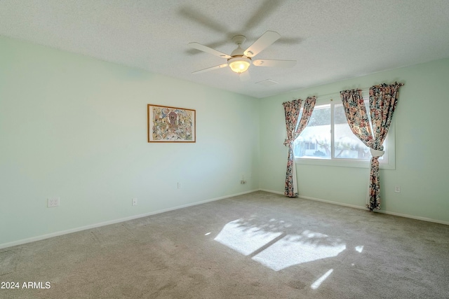 unfurnished room with light carpet, ceiling fan, and a textured ceiling