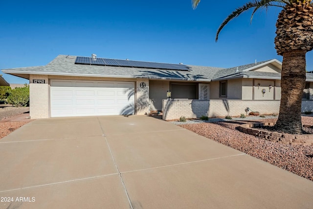 ranch-style home featuring solar panels and a garage