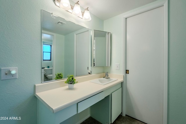 bathroom featuring a textured ceiling, vanity, and toilet