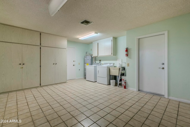 washroom featuring light tile patterned flooring, cabinets, separate washer and dryer, and a textured ceiling