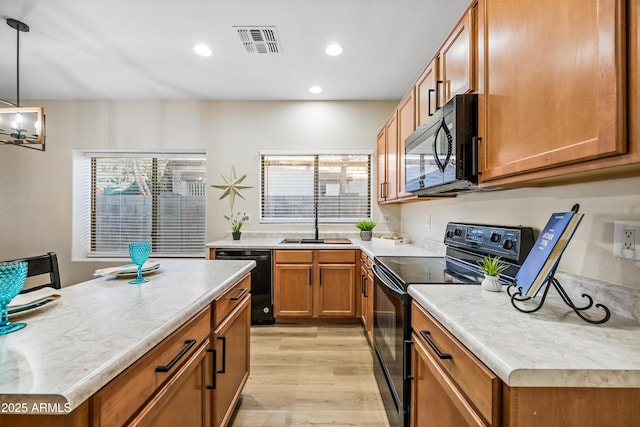 kitchen featuring a center island, black appliances, light hardwood / wood-style floors, sink, and hanging light fixtures