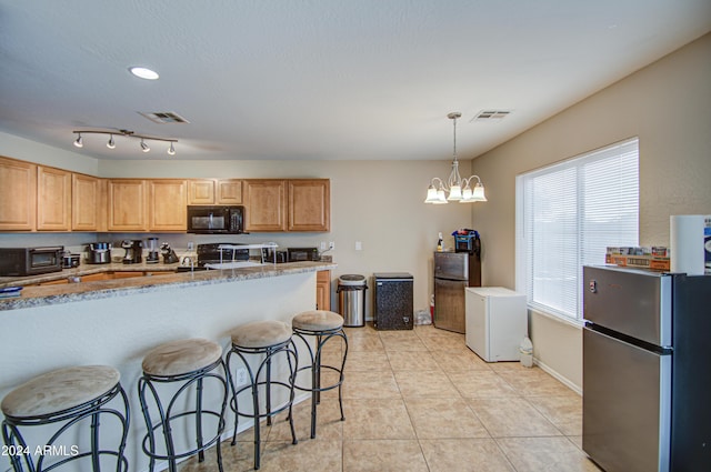 274 S 18th St, Coolidge, AZ 85128 - kitchen featuring light stone counters, black appliances, an inviting chandelier, hanging light fixtures, and a breakfast bar area
