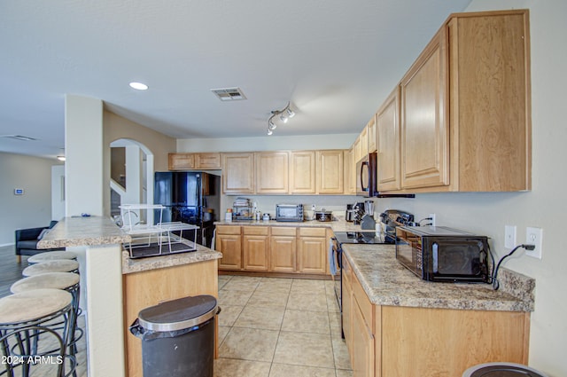 274 S 18th St, Coolidge, AZ 85128 - kitchen featuring light stone countertops, a kitchen bar, light brown cabinetry, light tile patterned floors, and black appliances