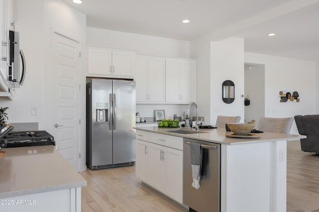 kitchen featuring stainless steel appliances, white cabinetry, sink, and an island with sink