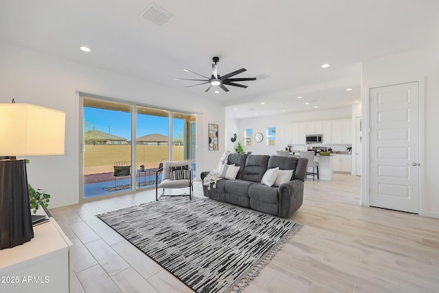 living room featuring ceiling fan and light hardwood / wood-style flooring