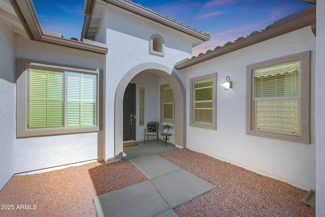 exterior entry at dusk featuring a patio