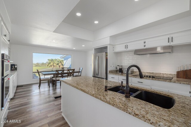 kitchen featuring white cabinets, sink, light stone countertops, light hardwood / wood-style floors, and stainless steel appliances