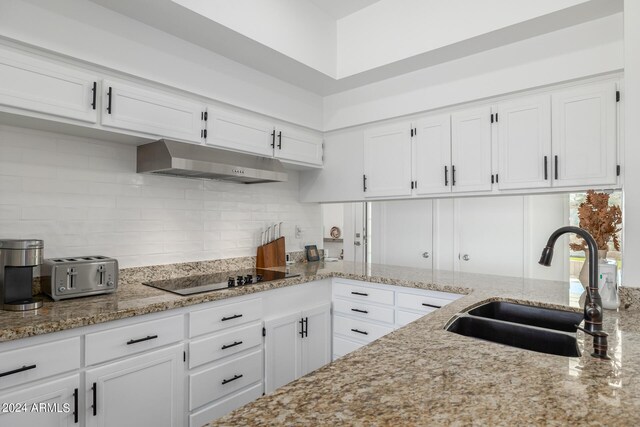 kitchen with white cabinets, black electric cooktop, light stone countertops, and sink