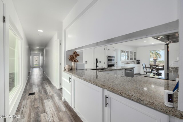 kitchen with light stone countertops, white cabinetry, and stainless steel appliances