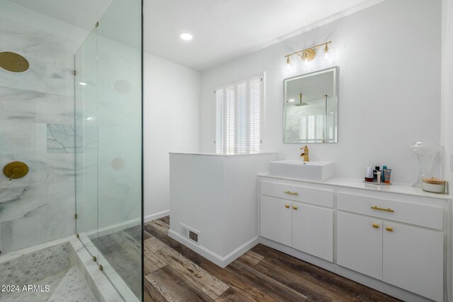 bathroom with hardwood / wood-style floors, vanity, and tiled shower