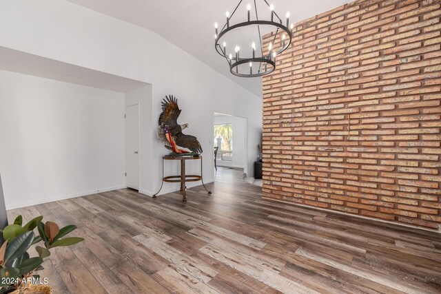 unfurnished dining area featuring dark hardwood / wood-style flooring, lofted ceiling, and an inviting chandelier