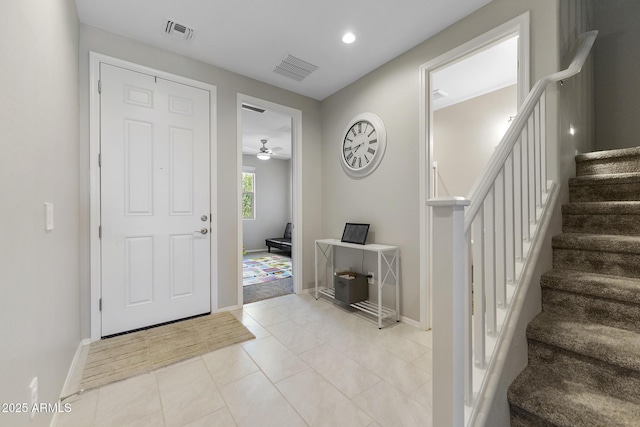 entryway featuring light tile patterned floors, visible vents, a ceiling fan, and stairs