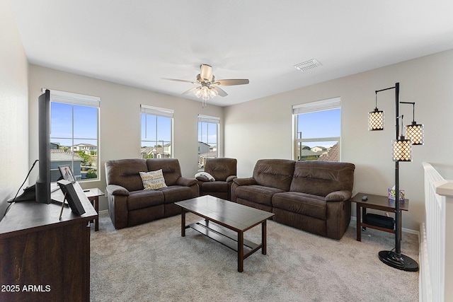 living area featuring a ceiling fan, plenty of natural light, light colored carpet, and visible vents