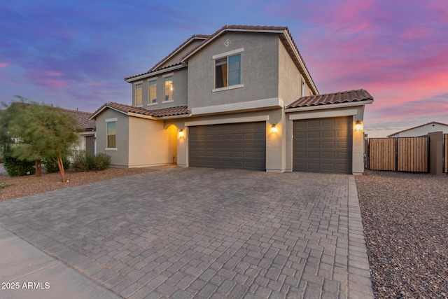 view of front of house with stucco siding, a tiled roof, driveway, and a gate