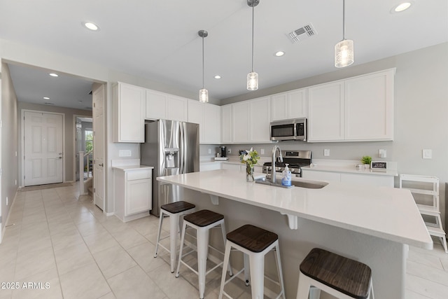 kitchen with visible vents, a kitchen bar, a sink, appliances with stainless steel finishes, and light countertops