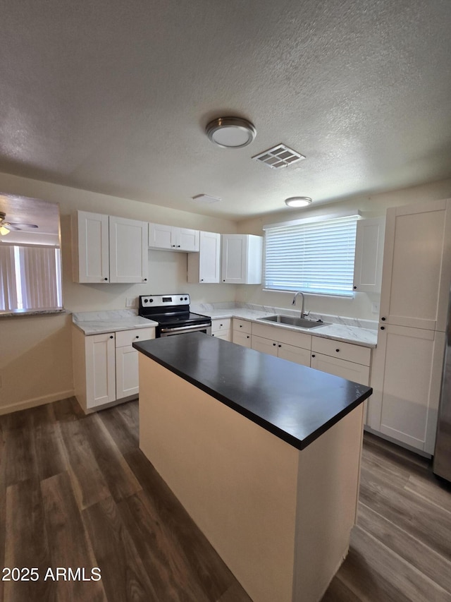 4911 W Merrell St, Phoenix, AZ 85031 - kitchen with electric stove, dark wood finished floors, a kitchen island, white cabinets, and a textured ceiling