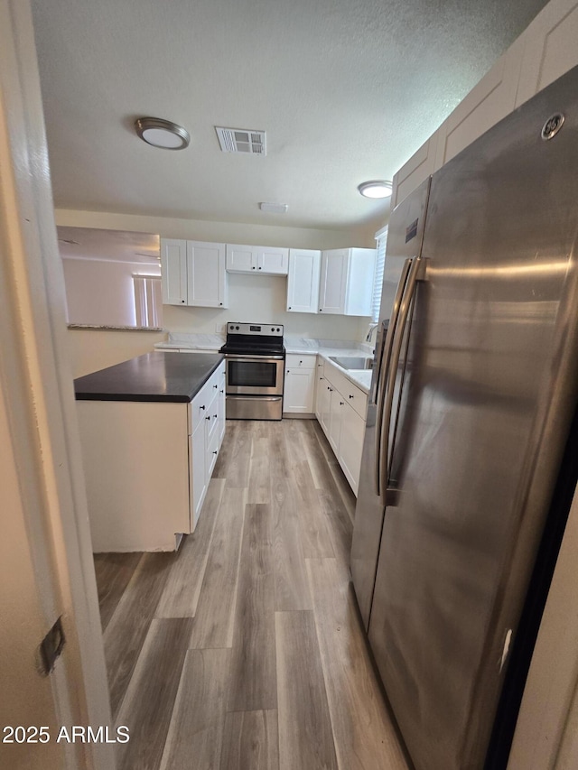 4911 W Merrell St, Phoenix, AZ 85031 - kitchen featuring appliances with stainless steel finishes, light wood-type flooring, and white cabinetry