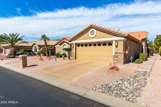 mediterranean / spanish-style house featuring an attached garage, concrete driveway, stone siding, a tiled roof, and stucco siding