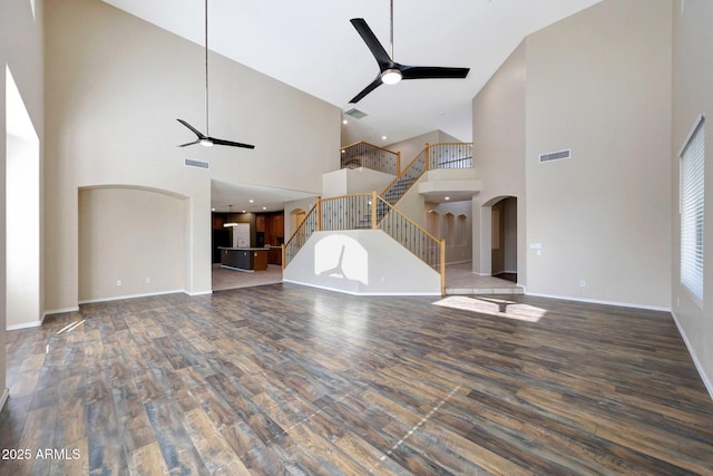 5726 W Park View Ln, Glendale, AZ 85310 - unfurnished living room featuring ceiling fan, high vaulted ceiling, arched walkways, wood finished floors, and stairway