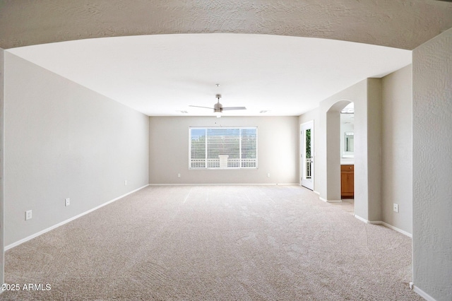 5726 W Park View Ln, Glendale, AZ 85310 - spare room with arched walkways, light colored carpet, a ceiling fan, and baseboards