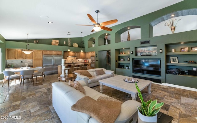 living room with ceiling fan, high vaulted ceiling, and built in shelves