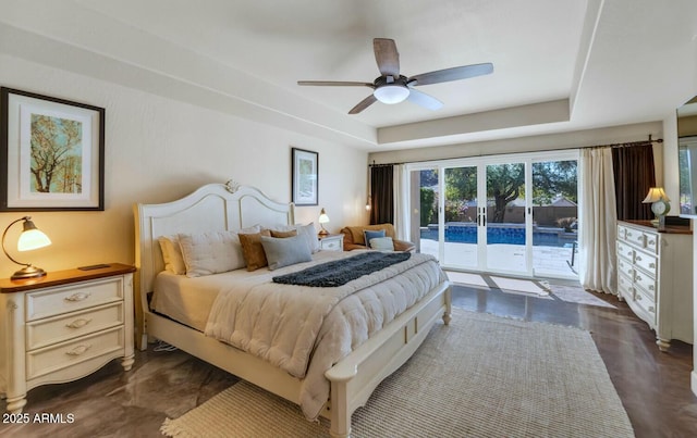 bedroom with ceiling fan, a tray ceiling, and access to outside