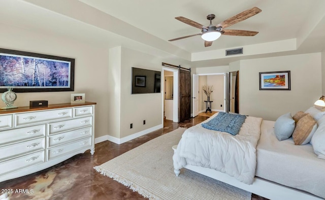 bedroom with ceiling fan, a tray ceiling, and a barn door