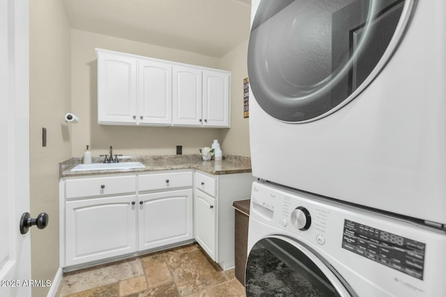 laundry room featuring cabinets, sink, and stacked washer and dryer