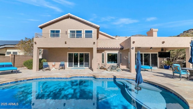 back of property featuring ceiling fan, a patio area, and a balcony